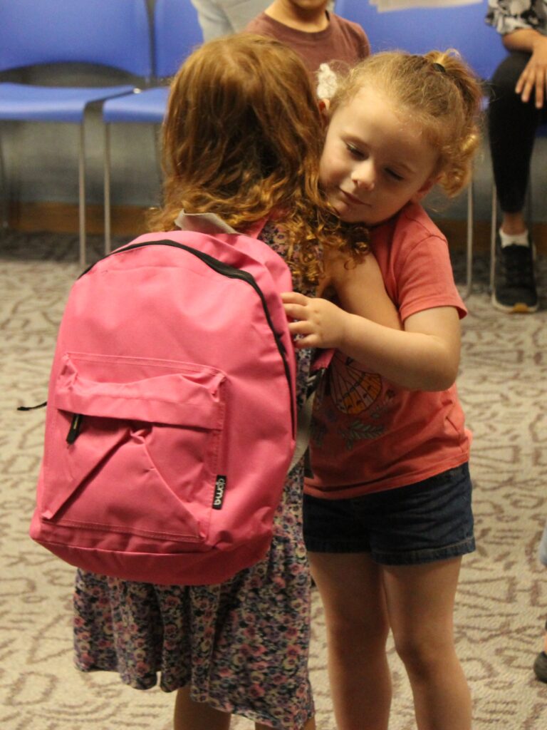 Two preschool-age children hug one another.