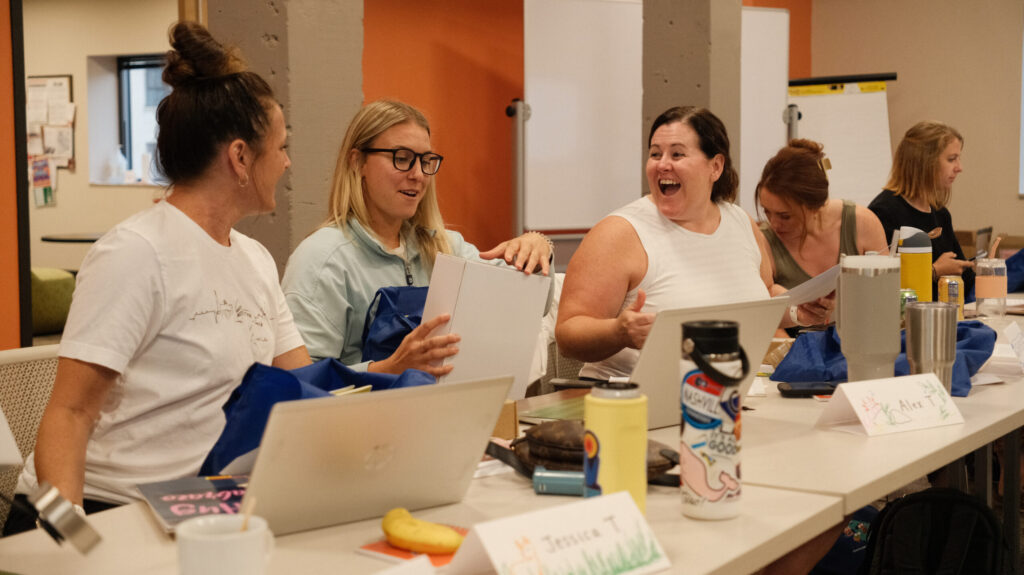 Educators at a professional learning event excitedly review educational materials together.