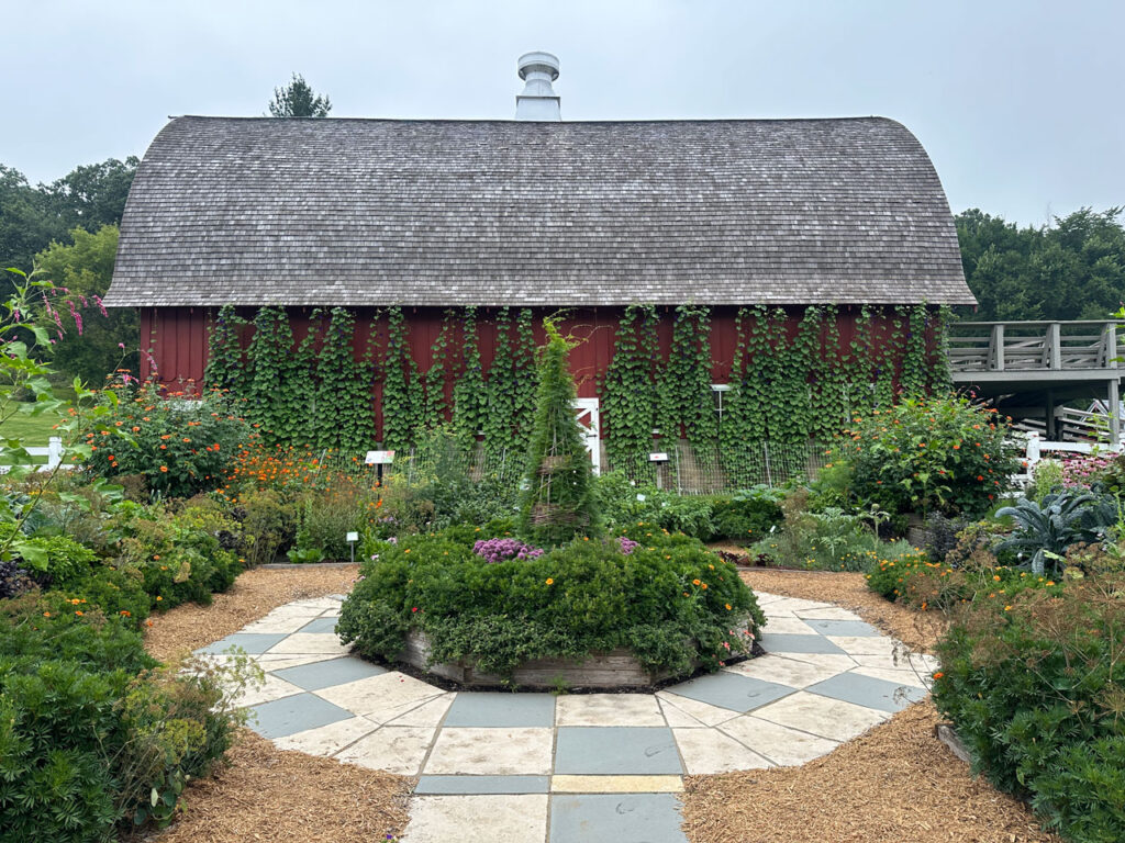 Beautiful gardens in front of a red barn.