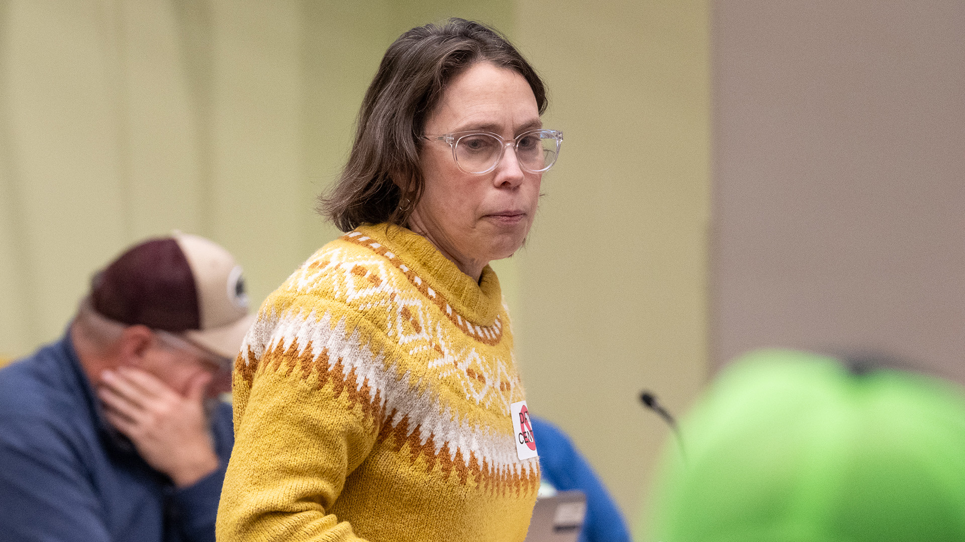 Lydia Reid stands in a room with out-of-focus people seated in front and behind her.