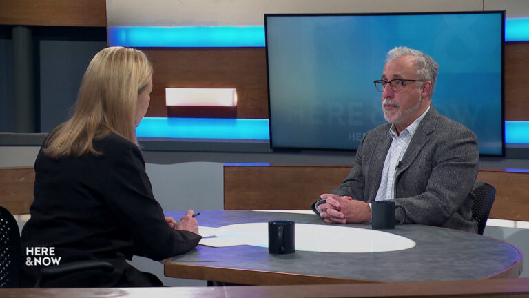 Frederica Freyberg and Howard Schweber sit facing each other on the Here & Now set.
