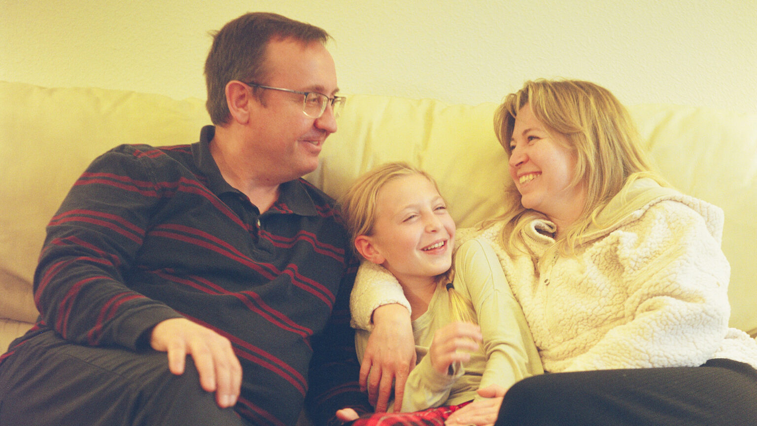 Sasha Druzhyna, Varya Mykhailova and Anna Mykhailova sit next to and face each other on a couch.