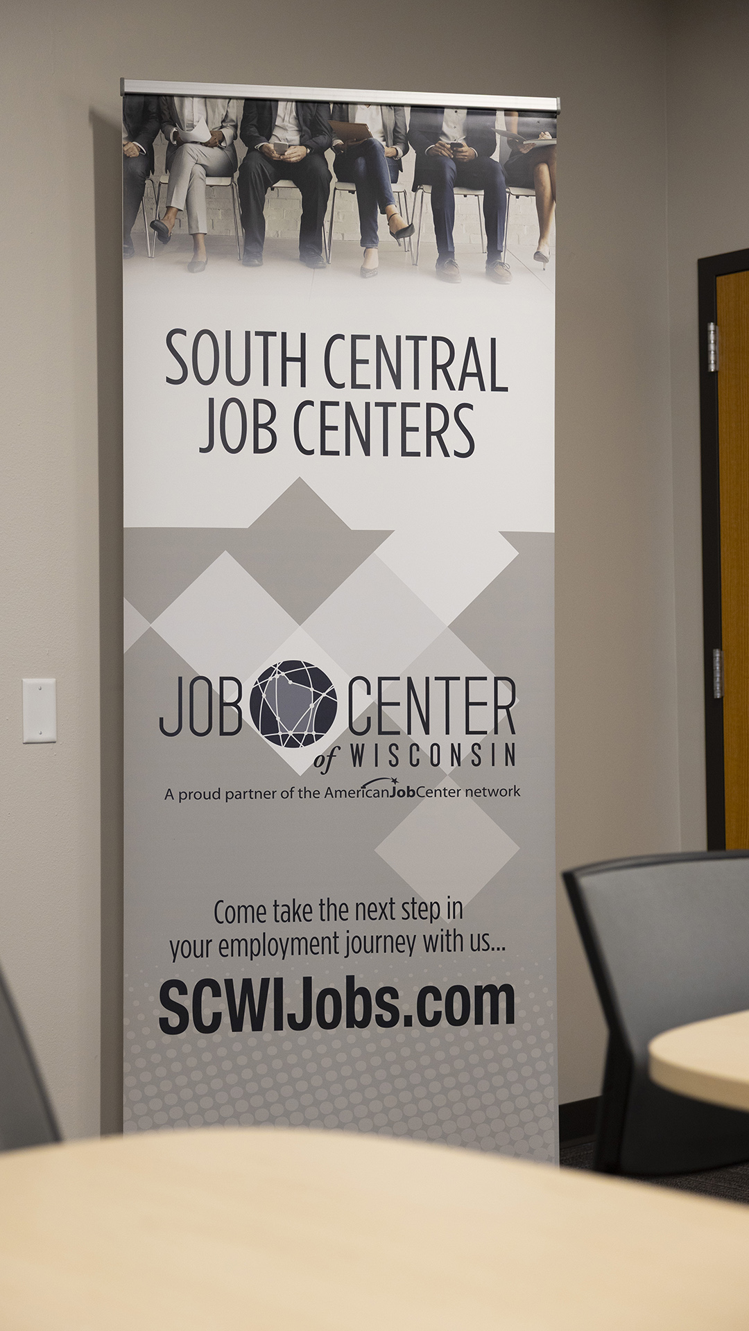 A vertical promotional banner shows an image of people seated in chairs, the title text "South Central Jobs Centers," a Job Center of Wisconsin wordmark, and text reading "Come take the next step in your employment journey with us... SCWIJobs.com."