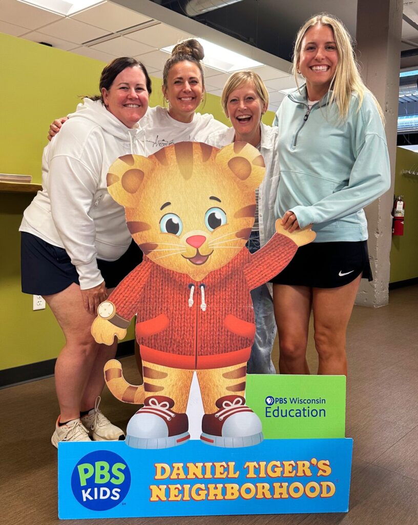 Four women stand behind a cutout of the PBS KIDS character Daniel Tiger