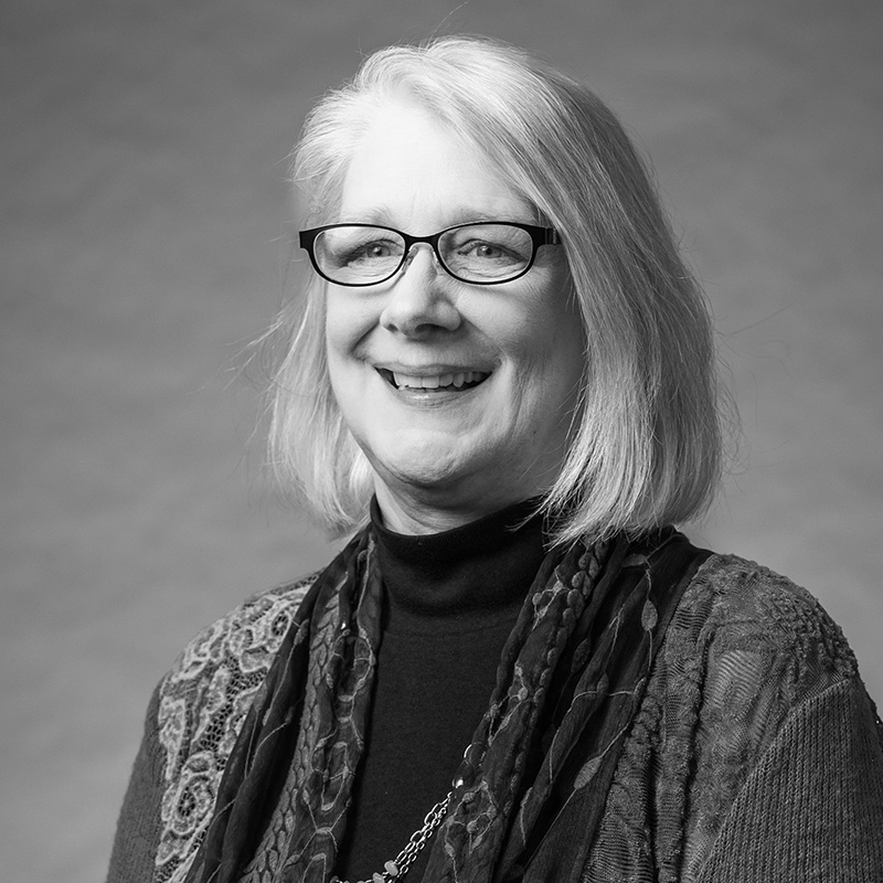Kathy Bissen, Ex-Officio Black-and-white headshot of Kathy Bissen, smiling, with short light-colored hair, glasses, and a patterned cardigan and scarf.