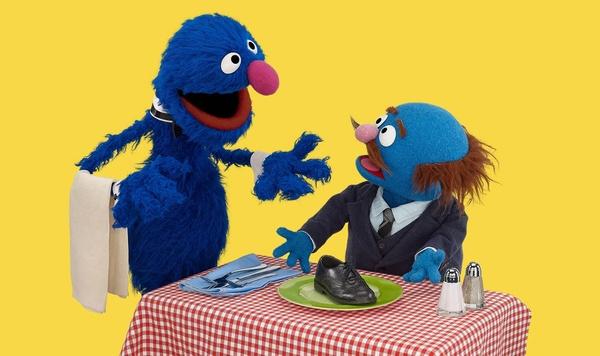 Grover waits on another muppet at a table.