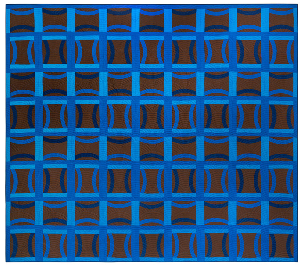 A blue and brown Double Wedding Ring quilt featuring a strong grid-like pattern due to the contrasting colors in the fabric.