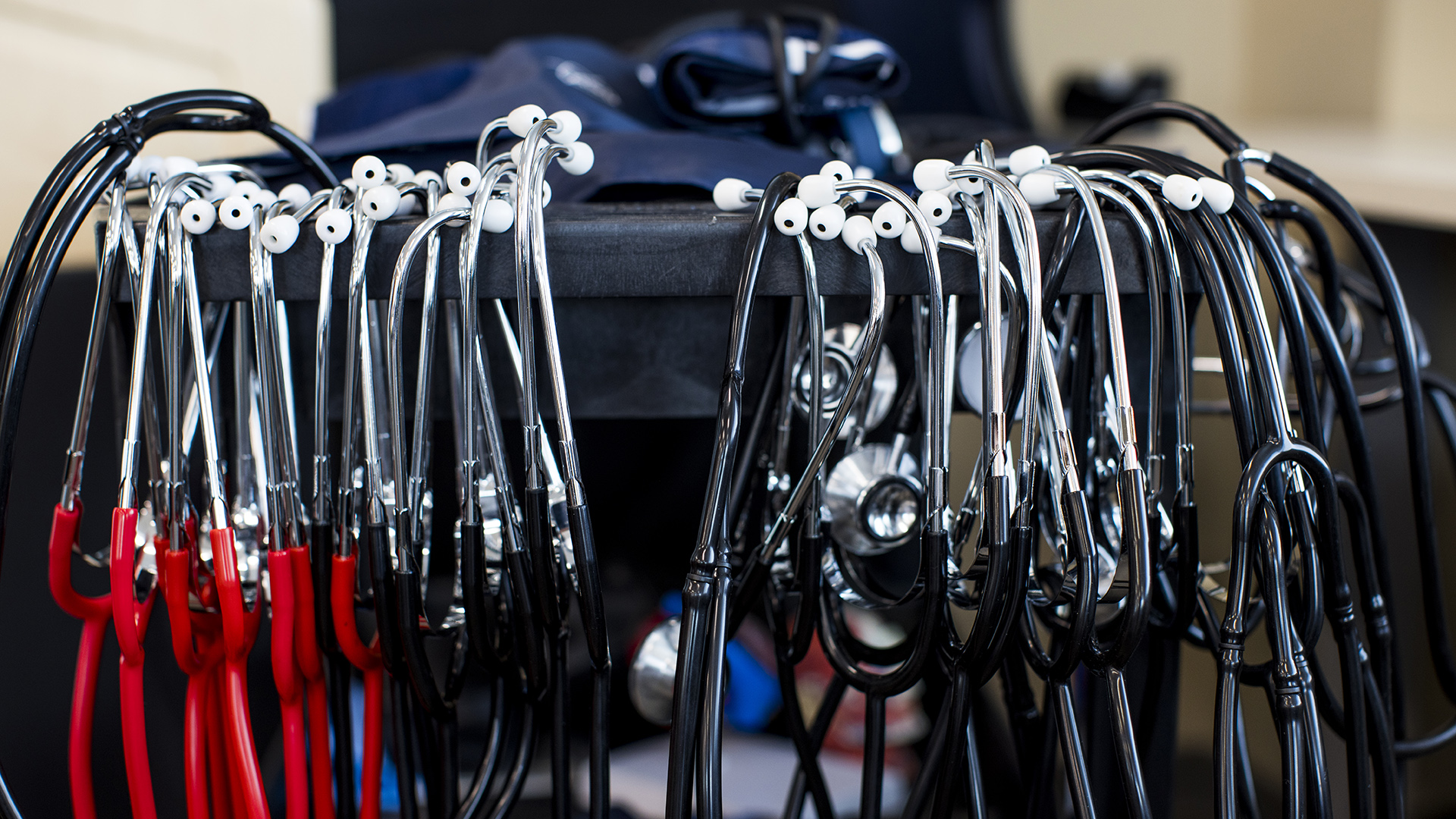 Multiple stethoscopes hang from the edge of a plastic rack.