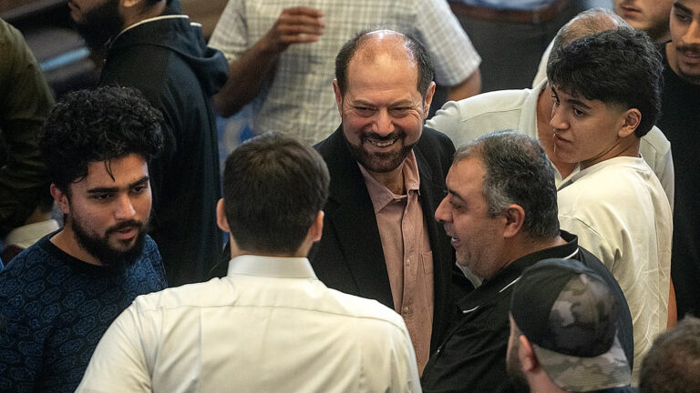 Salah Sarsour smiles while standing among a group of men speaking with him.