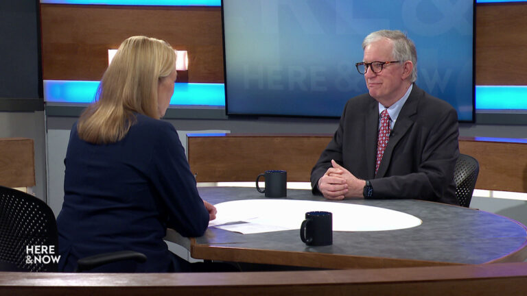 Frederica Freyberg and Charles Franklin sit facing each other on the Here & Now set.