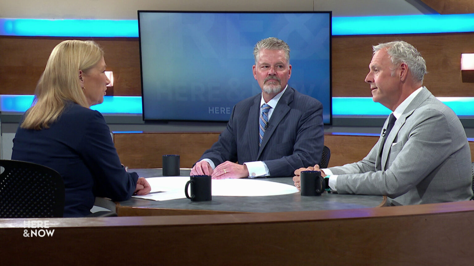 Bill McCoshen and Scot Ross sit next to each other and across from Frederica Freyberg at a desk on the Here & Now set. Bill McCoshen and Scot Ross sit next to each other and across from Frederica Freyberg at a desk on the Here & Now set.